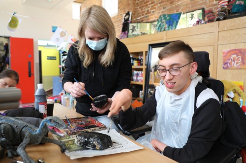 A teenage boy painting a rock black